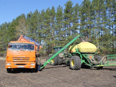 Тракторист Сергей Пиголин (наверху) и водитель Владимир Гусев загружают семенами посевной агрегат