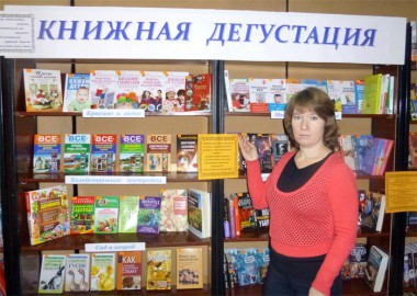 Заведующая отделом обслуживания в читальном зале Елена Сергеевна Масанова показывает книжную выставку и приглашает всех желающих её посетить.