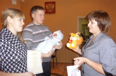 Начальник отдела ЗАГС Татьяна Комарова вручает молодым родителям Сергею и Екатерине Егоровым Свидетельство о рождении дочери Василисы и подарки