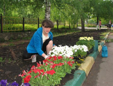 Специалист по землепользованию  поселковой администрации Татьяна Гребнева  высаживает разноцветные петунии
