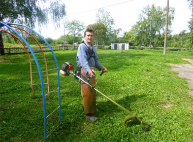 Владислав Александрович Павлов обкашивает траву на территории Холязинского детского сада