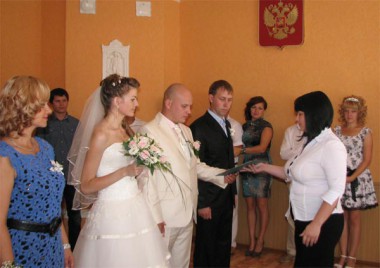 Церемонию бракосочетания проводит Ирина Владимировна Нужнова: она вручает главе новой семьи свидетельство о заключении брака